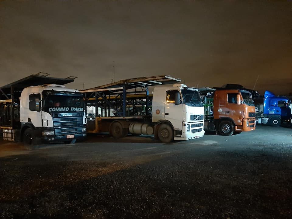 Caminhões cegonha da Goianão Transportes estacionados no pátio à noite
