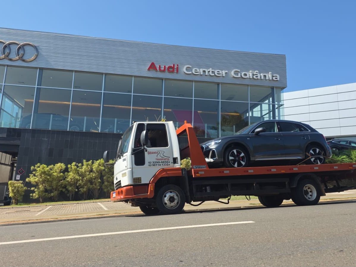 Guincho plataforma da Goianão Transportes levando um SUV em frente a uma concessionária em Goiânia