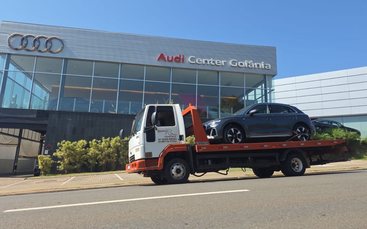 Guincho plataforma da Goianão Transportes levando um SUV em frente a uma concessionária em Goiânia